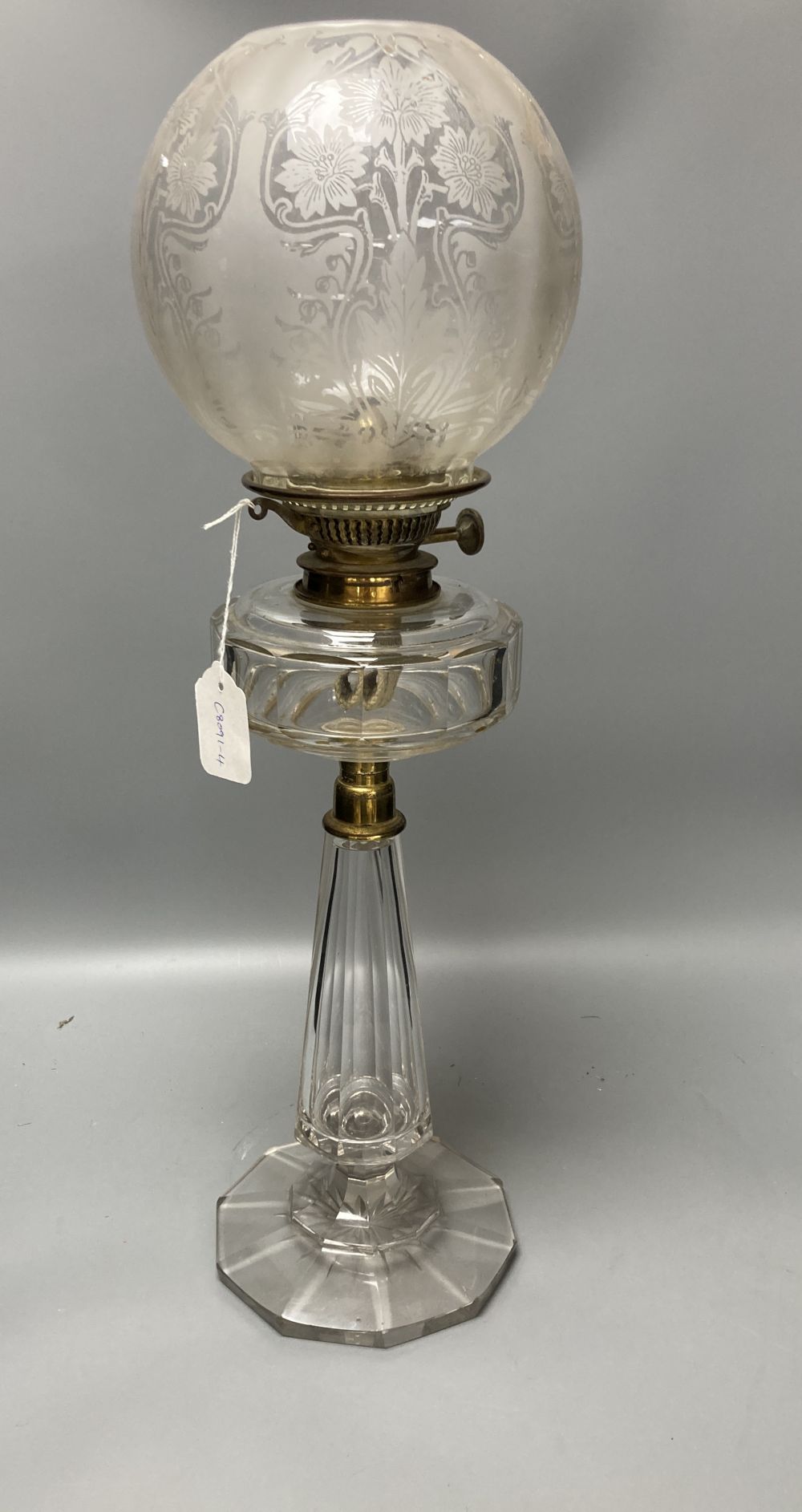 A late 19th century cut glass oil lamp with floral embossed shade, 61cm high including shade